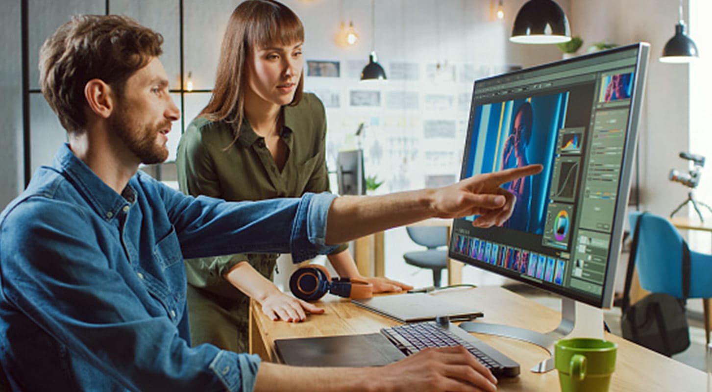 Two professionals focused on a computer screen in an office environment.